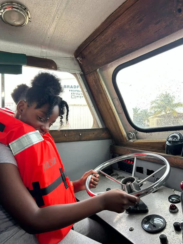 Student exploring the controls of a vessel while wearing a life jacket